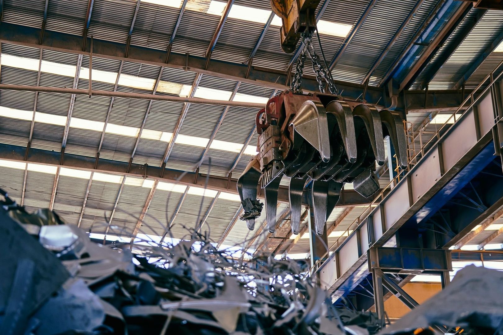 Overhead grapple lifting scrap metal inside an industrial recycling facility